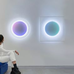 a woman sitting on a blue chair in front of two colorful circles that appear to be floating