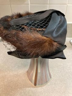 What a fabulous dressy stylish vintage ladies hat!.  This hat features a net veil that can be worn over face or tucked inside the hat. Mink/sable fur ( not certain) with black satin trim. This small hat is intended to be worn sitting atop the head. Often worn a little forward with veil. This vintage hat is small. 6 inches across- slightly expands so the hat will fit snug when in place.  Please see the photos as part of the description. In very well cared for cherished condition. Winter Evening Brimmed Mini Hats, Vintage Wide Brim Costume Hat For Evening, Winter Evening Brimmed Fascinator, Victorian Cloche Hat For Evening, Vintage Party Hats For Winter, Vintage Hats For Royal Ascot Evening, Vintage Evening Hat For Royal Ascot, Vintage Top Hat For Kentucky Derby Evening, Vintage Evening Hats For Royal Ascot