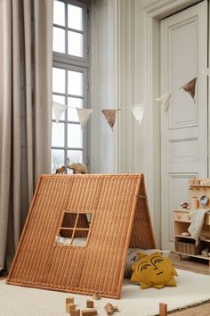 a child's play house made out of wickers and wood blocks in front of a window