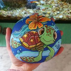 a hand holding a painted rock with a turtle on it