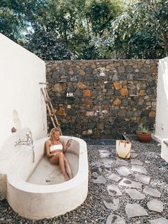 a woman is sitting in the bathtub outside