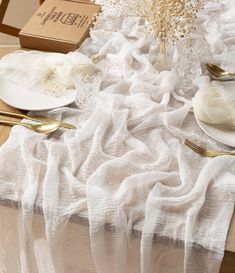 the table is set with white linens and goldware