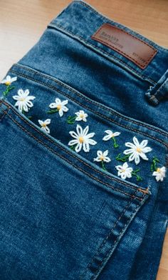 a pair of jeans with daisies embroidered on them