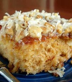 a blue plate topped with a piece of cake covered in nuts and coconut flakes