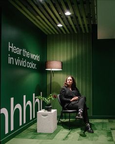 a woman sitting on a chair in front of a green wall with the words hhl