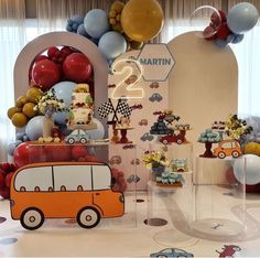 a birthday party with cars and balloons on the wall, cake table and dessert display