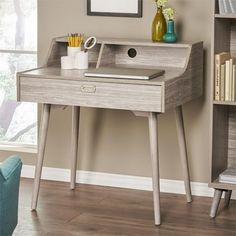 a desk with a laptop on it in front of a bookshelf and window