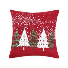 a red pillow with white trees on it and snow flakes in the sky above