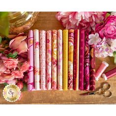 a bunch of different colored papers sitting on top of a wooden table next to flowers