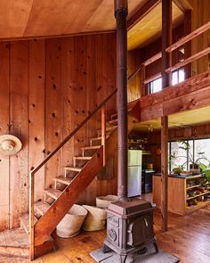 a wood burning stove sitting in the middle of a living room next to a stair case