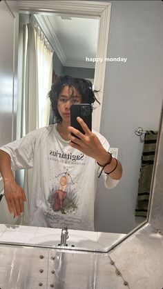 a young man taking a selfie in front of a mirror with his cell phone