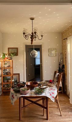 an open door leading into a dining room with lights on the ceiling and table covered in food