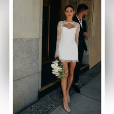 a woman in a short white dress is walking down the street with a man wearing a suit and tie