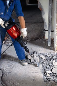 a man using a power drill to fix a hole in the ground that has been filled with cement