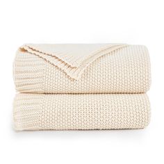 two blankets folded on top of each other in cream colored knits, with one blanket folded