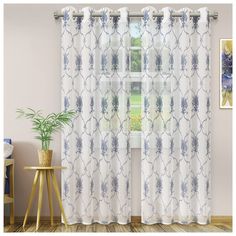 a living room with a window covered in blue and white patterned curtains next to a potted plant