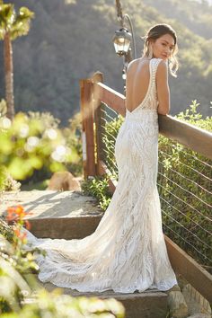 a beautiful woman in a white dress standing on steps looking at the camera with her back to the camera