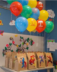 some balloons are hanging from the ceiling in front of bags with stickers on them