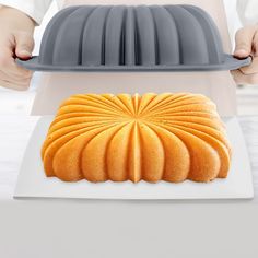 a person holding a cake pan with a bundt cake on it in front of them