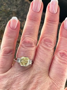 a woman's hand with a yellow diamond ring on top of her left hand