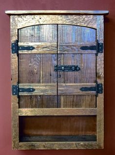 an old wooden cabinet with metal handles and latches on the doors, against a red wall