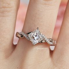 a woman's engagement ring with a princess cut diamond in the center and pave set diamonds on each side