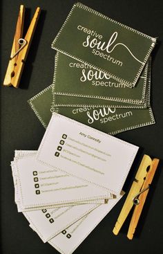 several business cards and clothes pins are on a table with some paper clippings