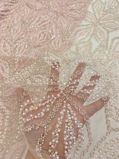 the back of a dress with pearls and beading on it, sitting on top of a table