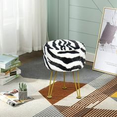 a zebra print stool sitting on top of a rug next to a painting and books