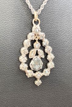 A Victorian diamond pendant with a platinum setting C1880. An outer ring of rose cut diamonds 15 in number and about 2mm of the diamond visible . The setting folds around the stone. In the centre, hanging by a gold loop and bale , are one round diamond, two smaller pair shaped diamonds and a large pear shape diamond approximately 6mm by 5mm.  All diamonds are rose cut. The central pear shape diamond has carbon inclusions visible with the magnifying glass. The chain is a modern addition., 16 inches long. The pendant is 31mm ( 1.2 inch ) into bale long and 16 mm Max, wide (0.64 inch) Total weight 7.4 gms Antique White Gold Diamond Necklace With Single Cut Diamonds, Antique White Gold Diamond Necklace, Victorian Diamond Necklace With Single Cut Diamonds, Antique Pendant Diamond Necklace With Accents, Antique White Gold Diamond Pendant Necklace, Antique Diamond Pendant Necklace With Accents, Wedding Rose Cut Diamond Platinum Necklace, Wedding Platinum Necklace With Rose Cut Diamonds, Platinum Rose Cut Diamond Necklace For Wedding