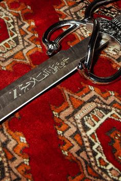 a pair of scissors sitting on top of a red rug next to a metal object