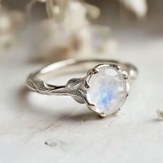 a close up of a ring on a table with flowers in the background and a white flower