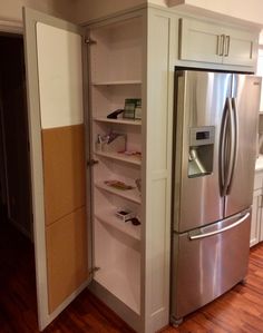 a stainless steel refrigerator and freezer combo in a kitchen with hardwood floors, white cabinets and wood flooring