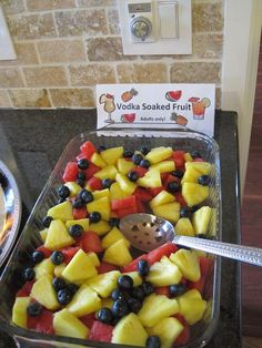 a tray filled with fruit next to a sign that says vodka soaked fruit