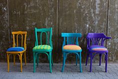 four colorful chairs lined up against a wall