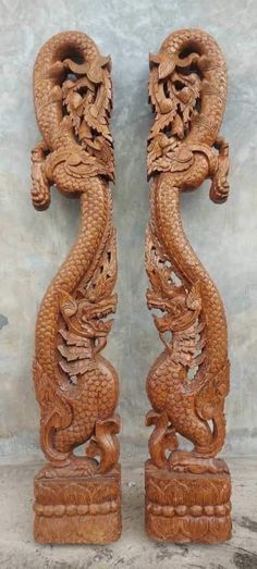 two carved wooden dragon sculptures sitting on top of a cement floor next to each other