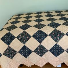 a bed with a blue and white quilt on it's headboard next to a wall