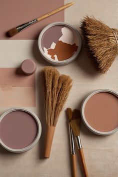 some paint and brushes on a table with different shades of pink, brown and white