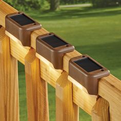 three mailboxes are placed on the top of a wooden fence in front of a green lawn