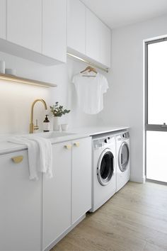 a washer and dryer in a white laundry room next to a large window