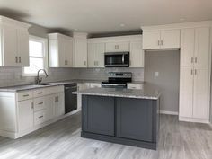 an empty kitchen with white cabinets and gray counter tops