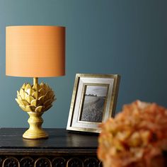 a lamp sitting on top of a wooden table next to a framed photo and a vase