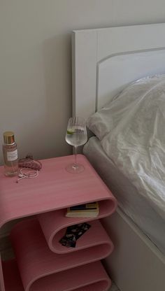 a pink table with three wine glasses on it and a bed in the back ground