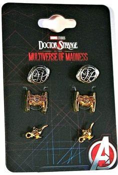 three pairs of gold and silver metal earrings on a black card with an ad for doctor strange's multiverse of madness