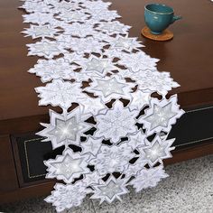 the table runner is decorated with white snowflakes on it, along with a teapot