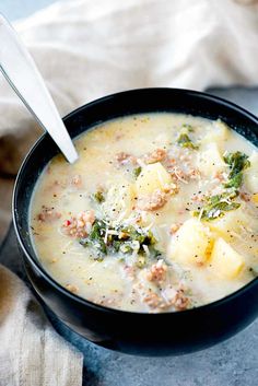 a bowl of soup with broccoli, potatoes and meat in it on a table