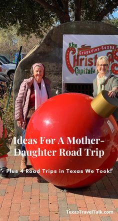 two women standing next to a big red ball