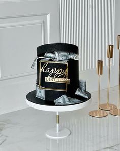 a black and gold birthday cake sitting on top of a table