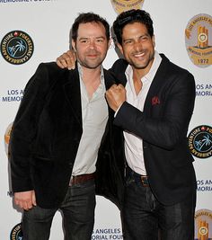 two men standing next to each other on a red carpet