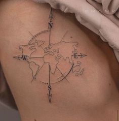 a woman's back with a compass tattoo on her left side ribcage